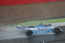 Photo d'une monoplace bleue sur une piste détrempée, soulevant des gerbes d'eau.