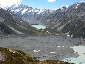 Il Mueller Glacier (sotto le macerie) e la sua morena (in primo piano), il Hooker Glacier e il suo lago terminale (sullo sfondo) e l'Aoraki / Mount Cook, sullo sfondo.