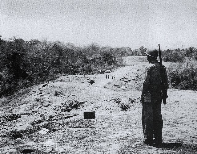 A U.S. Marine stands near some of the fighting positions on Hill 123 on "Edson's" Ridge after the battle. Edson's command post during the battle was l