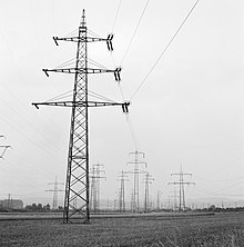 In the 1920s the RWE started the construction of a national power transmission grid in Germany. In the front a 220/110 kV pylon in the typical three-level design of the company. Hoogspanningsmasten in een veld nabij Koblenz, Bestanddeelnr 254-1007.jpg