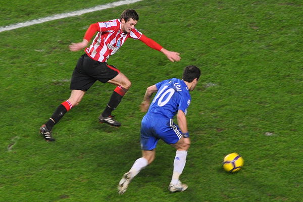 Cole, playing for Chelsea, taking on Sunderland player George McCartney