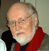 Composer John Williams, balding, with a beard and wearing glasses looking directly at the camera