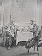 Due uomini seduti a un tavolo in una conversazione in una sala ristorante.  Uno fuma a gambe incrociate sotto un cartello vietato fumare, l'altro si gode un piatto.
