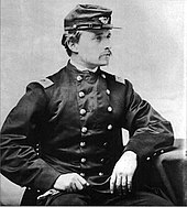 Photographie noir et blanc en buste, assis, d'un homme blanc moustachu en uniforme des armées Nordistes, coude posé sur un siège et l'autre main sur les genoux