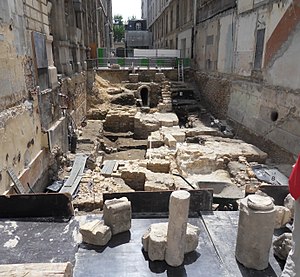 Vue générale du chantier de fouilles en juin 2013. Niveaux successifs : zone romaine, terre agricole du cloître avec une pierre tombale encore en place, début du chœur, extrémité de la nef,