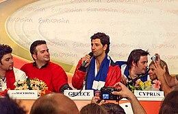 סאקיס רובאס מדבר במסיבת העיתונאים של 10 העולות לשלב הגמר באירוויזיון 2004 מיד בתום מופע חצי הגמר