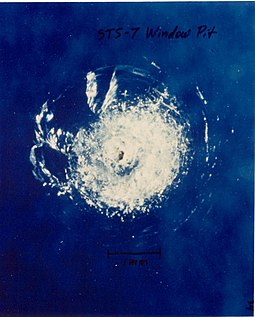 A micrometeoroid left this crater on the surface of Space Shuttle Challenger's front window on STS-7. Space debris impact on Space Shuttle window.jpg