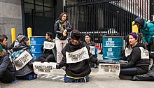 A sleeping dragon protest in February 2018. Protestors have locked arms through a combination of pipes and barrels. Stop ICE rally SF 20180228-0531.jpg