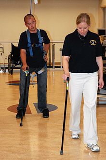 A man with two prosthetic legs uses a hands-free harness walking gait training device during a therapy session US Navy 071015-N-5086M-202 Retired Marine Corps Cpl. Timothy Jeffers walks on his prosthetic legs while using the hands-free harness walking gait training device during a therapy session in the new Comprehensive Combat and Com.jpg