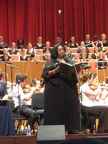 Orkestra eşliğinde performans sergileyen Afrikalı Amerikalı şarkıcı