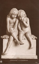Frontalansicht einer Skulptur, die eine Kindergruppe darstellt, zwei kleine Kinder sitzen auf einem Podest