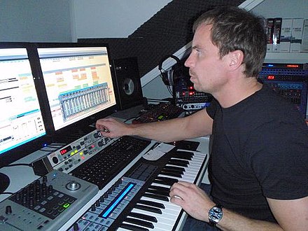 Music production in the 2000s using a digital audio workstation (DAW) with an electronic keyboard and a multi-monitor set-up