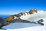 Zugefrorener See in der Wiege eines schneebedeckten Berges mit zerklüfteten Felsgipfeln
