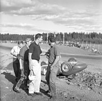 Joakim Bonnier byl profesionálním závodním jezdcem v roce 1958 a závodil na MS F1 i na MS sportovních vozů. Do Kanonloppetu v Karlskoze přijel v srpnu se svým starým dvoulitrovým Maserati 200SI, které vlastnil jeho přítel a multimilionář Ulf Norinder. Na snímku je vidět Bonnier (s helmou), jak uklidňuje Norindera. 1958.