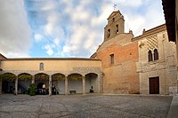 Compás o atrio. A la derecha la fachada de Alfonso XI]] Se accede al edificio por un patio o compás (se cree que era el antiguo patio de armas del palacio), donde se encuentra la fachada llamada de Alfonso XI, de la que se dice que fue el antecedente de la fachada del Alcázar de Sevilla. En el cuerpo inferior está la puerta con un dintel adovelado y encima una inscripción de caracteres árabes. A ambos lados hay dos lápidas (laudas) cristianas. En una de ellas está escrita la crónica de la Batalla del Salado. La escritura está muy deteriorada pero se han hecho estudios recientes para conseguir su trascripción. Sobre la puerta hay una ventana con [[ajimez‎‎}}