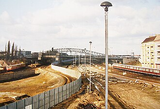 Ein S-Bahn-Zug der Reichsbahn (re.) befährt von Schönhauser Allee kommend die Verbindungsstrecke nach Pankow, westlich der Mauer fährt ein S-Bahn-Zug der BVG (li.) nach Gesundbrunnen (1990).