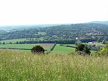 view of hills, trees and fields across a meadow