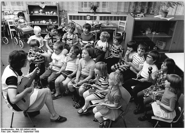 A German kindergarten teacher instructs her pupils in singing