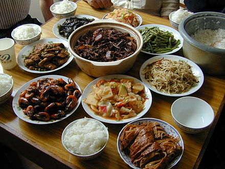 Un conxunto de pratos típicos da cociña chinesa: cuncos de arroz, gambas, berenxena e tofu fermentado, vexetais, pato e unha fonte central con carne e brotes de bambú