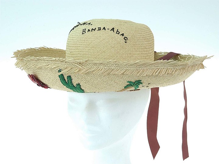 Woven hat from 'panama straw' with decorations in felt and cotton thread. The embroidered text says "Curaçao N.A. Banda-abao". Before 1963