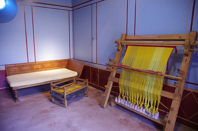 Reconstruction of a Roman loom. Warps have been chainstiched together; weights are resting on a low bench.
