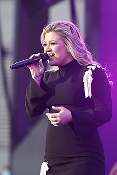 Musician Kelly Clarkson singing into a microphone