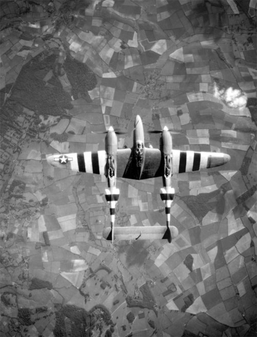 A USAAF photo-reconnaissance Lockheed F-5 Lightning in flight over Europe circa June 1944. It is marked with invasion stripes to help Allied troops cl