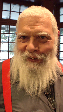 photo couleurs d'un homme au teint mat, aux cheveux blancs, avec une moustache et une longue barbe blanche
