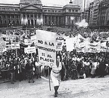 Maria Elena Oddone holding a banner, on International Women's Day in 1984 in Argentina. The banner says "No to motherhood, yes to pleasure". Maria Elena Oddone en 1984.jpg