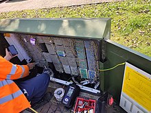 An engineer works at a VDSL cabinet Openreach Man at cabinet.jpg