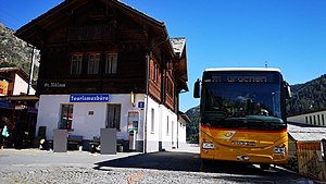 Zweistöckiges Gebäude mit Satteldach; Daneben steht ein Bus