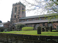 A stone Gothic church with a battlemented tower on the left