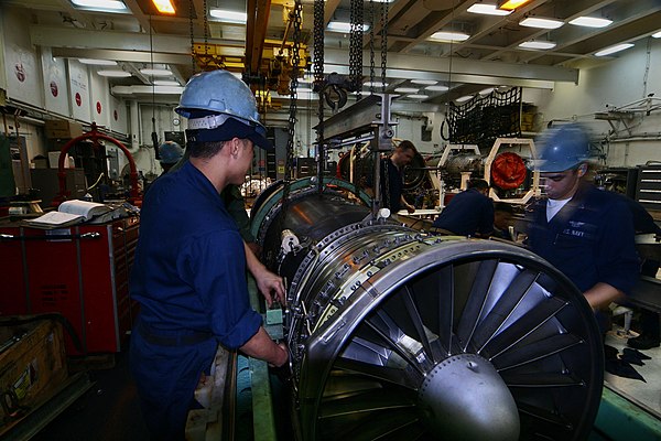 Sailors lower an F/A-18 Hornet engine into its container aboard the USS Kitty Hawk (CV-63)