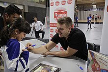 Hyman signing a book and a Maple Leafs jersey for a young reader ZachHymanBookSigningMagiciansSecret.jpg