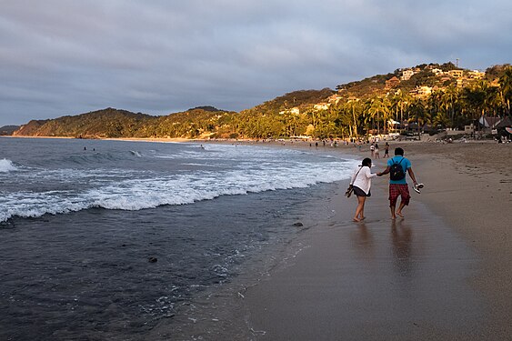 Couple walks down the beach in Sayulita at sunsent. State of Nayarit, Mexico.