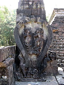 Bhima relief at Sukuh temple, a hero of the Mahabharata, who stands opposite a pedestaled god within a horseshoe-shaped arch. The figures are sculpted in wayang puppet style, resembling their. leather-puppet counterparts in posture, costume, and sideways presentation