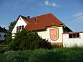 Haus am Ortsrand mit Ortswappen