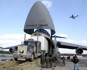 Airmen load the Aviation Combined Arms Tactical Trainer onto a C-5 Galaxy with the help of Army contractors, and a specially constructed ramp.