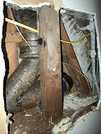 This view looking upwards through a hole in the ceiling shows a traditional leaded hub joint (at top) and a more recent rubber-sleeved hubless connection (at lower right).