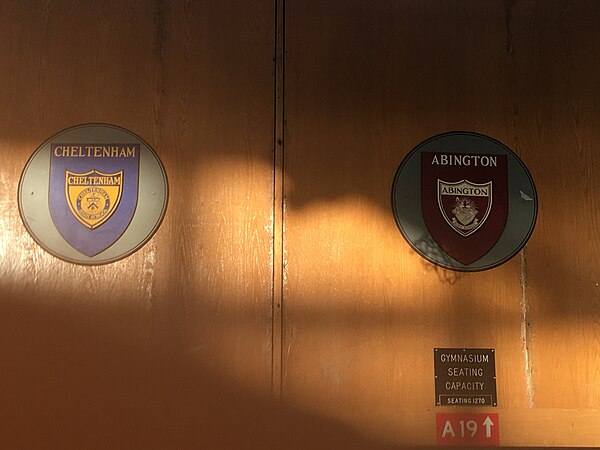 Cheltenham and Abington logos next to each other in the Abington gymnasium