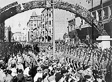 Soldiers marching past a large crowd