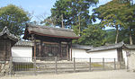 Малка дървена порта с покрив с мотиви от хризантема и фронтони в китайски стил отстрани.