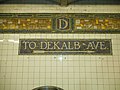 Directional mosaic at DeKalb Avenue (BMT Canarsie Line) to the street it was named for, under a "D" mosaic.