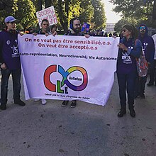 Hommes et femmes adultes derrière une banderole sur laquelle est inscrit « on ne veut pas être sensibilisé.e.s, on veut être accepté.e.s »