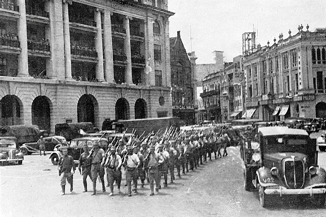 Japanese combatants march victoriously after the battle of Singapore through the city center.