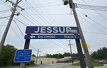 A blue and orange train station sign saying "Jessup" - rectangular shape