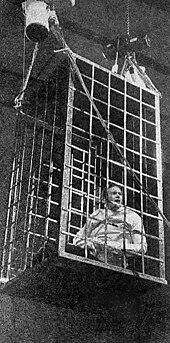 Cornette suspended above the ring in a shark cage during the 1988 Great American Bash on July 10. Jim Cornette shark cage by Roy London.jpg