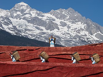 Mulheres do grupo étnico naxi carregando cestos; cena de uma apresentação pública no teatro ao ar livre da Montanha Nevada do Dragão de Jade. Lijiang, província de Yunnan, China. (definição 3 597 × 2 698)