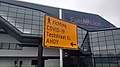 A route sign directing people to a major SARS-Coronavirus-2 testing facility in front of the stadium was originally the Eurovision Song Festival of 2020 was planned. It shows the contrast between planning for the future and having to deal with unforseen events. The site was at one moment planned to be a place where people celebrated international culture and life, but became a reminder of death ☠.