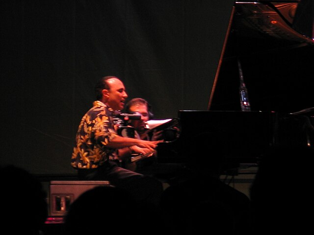 A man sitting in front of a piano, playing the keys.